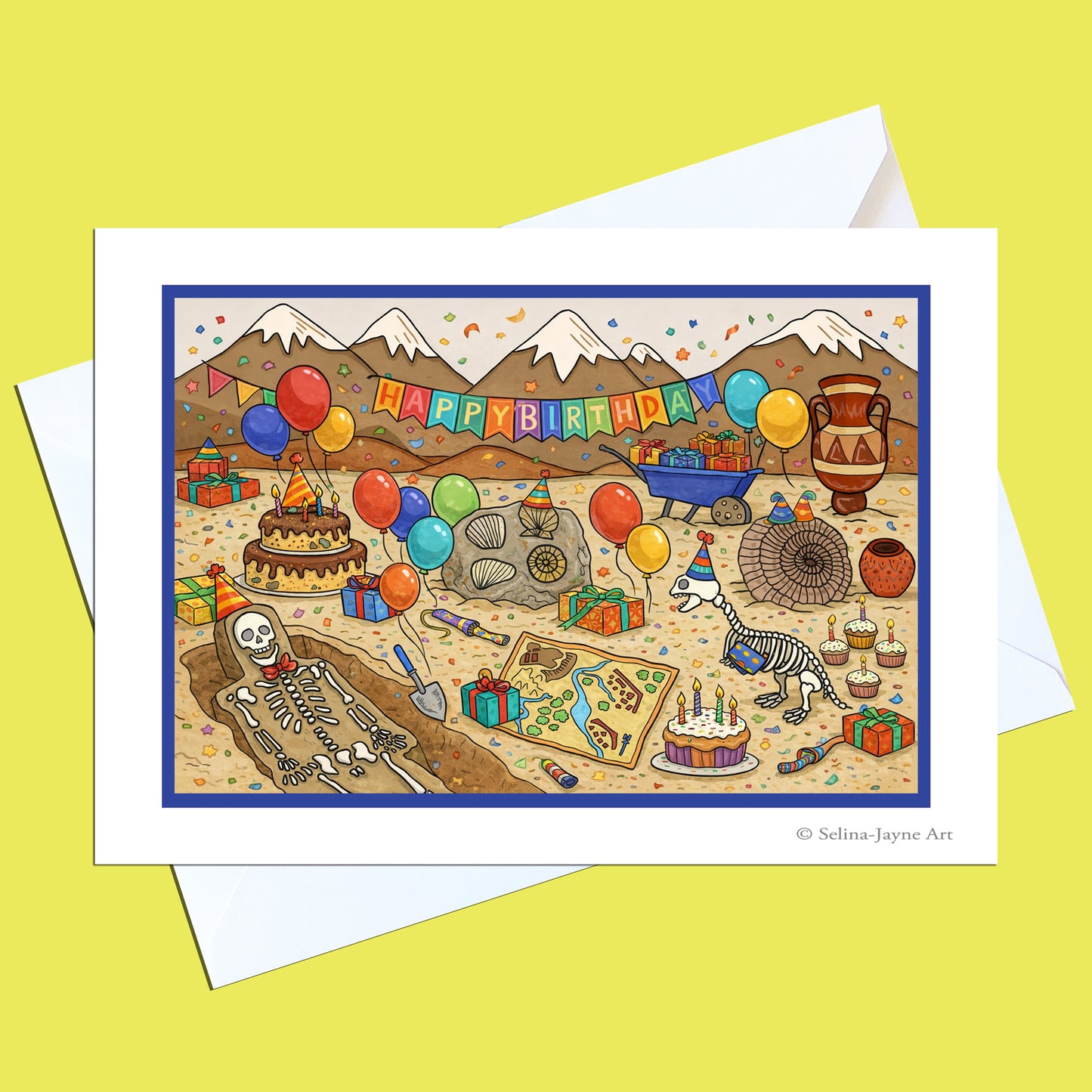 A square greeting card with a white border showing a colorful illustrated birthday scene with a skeleton, balloons, cake, mountains, and a 'HAPPY BIRTHDAY' banner, photographed on top of white envelopes against a pale yellow background.