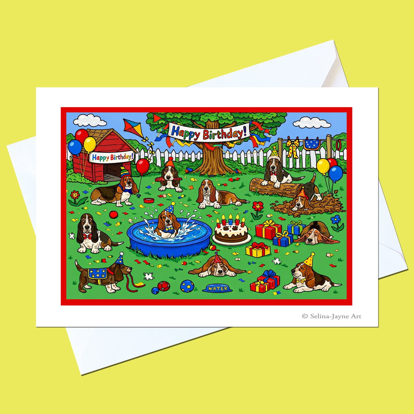 A square greeting card with a white border and white envelope, featuring a colorful cartoon birthday scene with English Springer dogs, balloons, a tree, fence, party hat, cake, and gifts. The card is photographed on a pale yellow background.