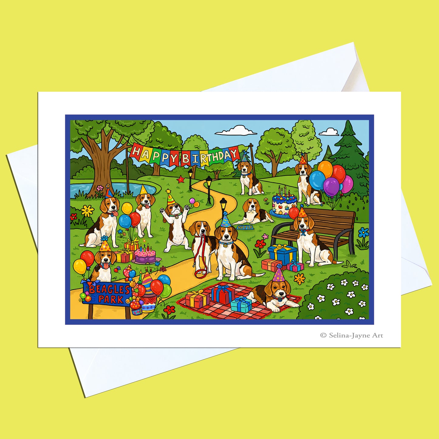 A square greeting card with a white border and white envelope, featuring a colorful cartoon birthday scene with dogs, balloons, gifts, trees, and a bench. The card is photographed on a pale yellow background.