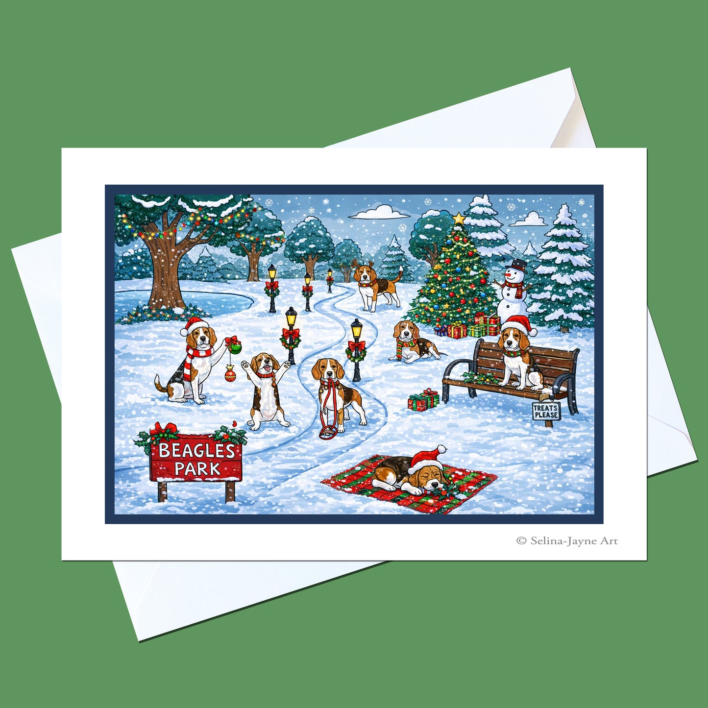 A Christmas-themed greeting card featuring an illustration of beagles in a snowy park decorated for the holiday, shown with a white envelope on a solid green background.