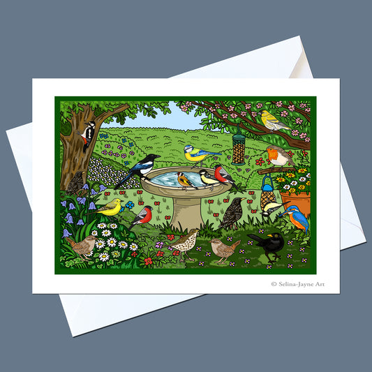 A square art print card featuring a colorful bird garden scene with birds around a birdbath, shown with white envelopes on a slate blue background. The print includes a visible artist signature in the lower right corner.