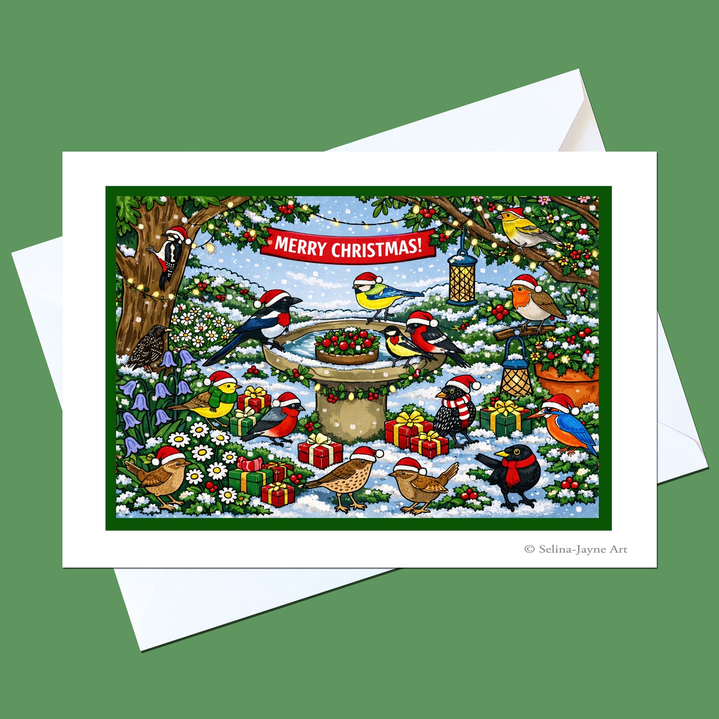 A Christmas bird-themed art print card with a white envelope, featuring colorful birds in a snowy winter garden with a birdbath and red 'MERRY CHRISTMAS!' banner, shown on a solid green background.