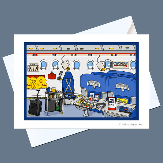 A printed art card showing a cartoon airplane cabin interior with blue seats, overhead bins, a luggage cart, and small details, displayed over white envelopes on a muted blue-gray background. Small text at the bottom right reads '© Selina Jayne Art'.
