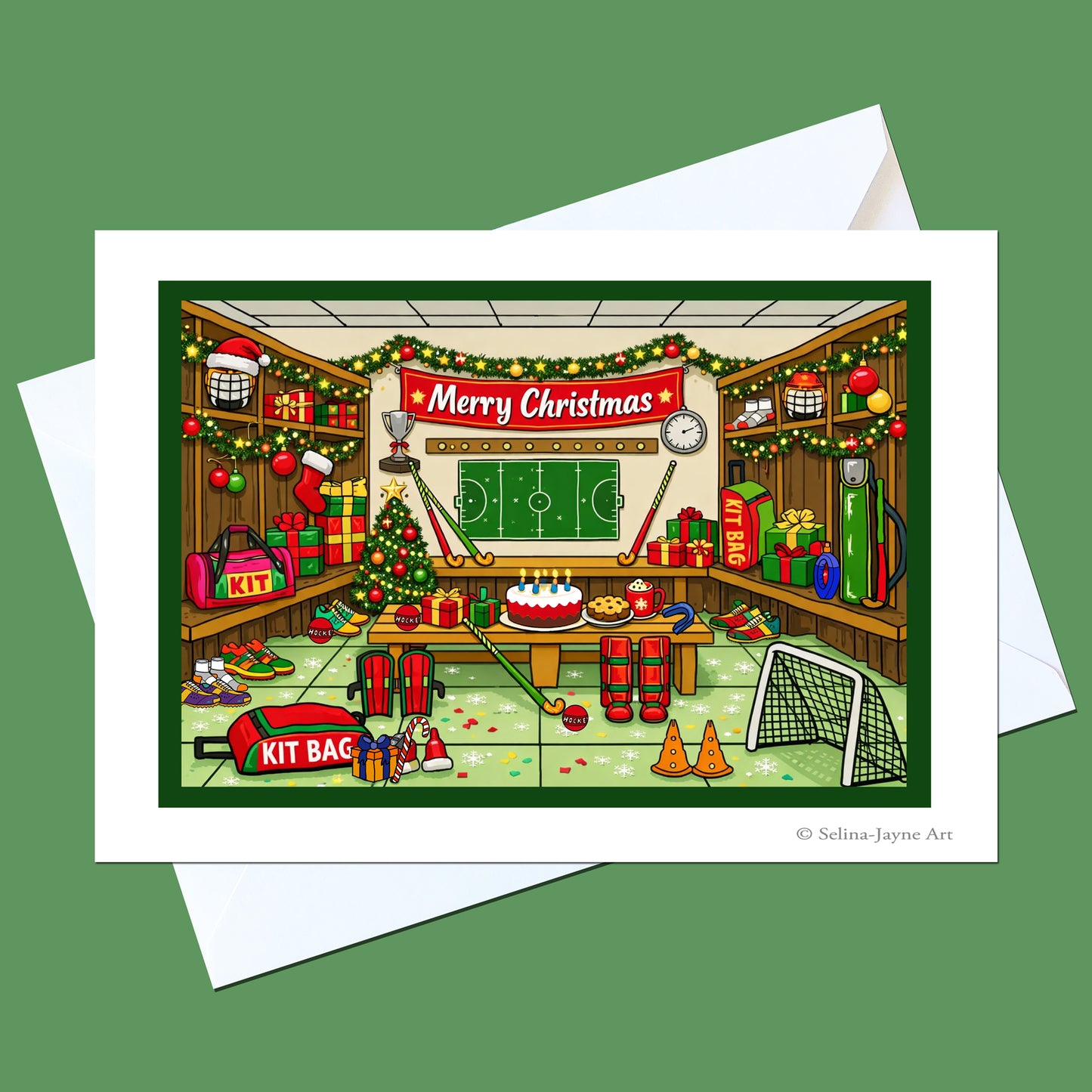 A square greeting card with a white border and white envelope, featuring a colorful cartoon illustration of a Christmas-themed football room. The room is decorated with garlands, gifts, a Christmas tree, a soccer ball, and a red banner that reads 'Merry Christmas'.