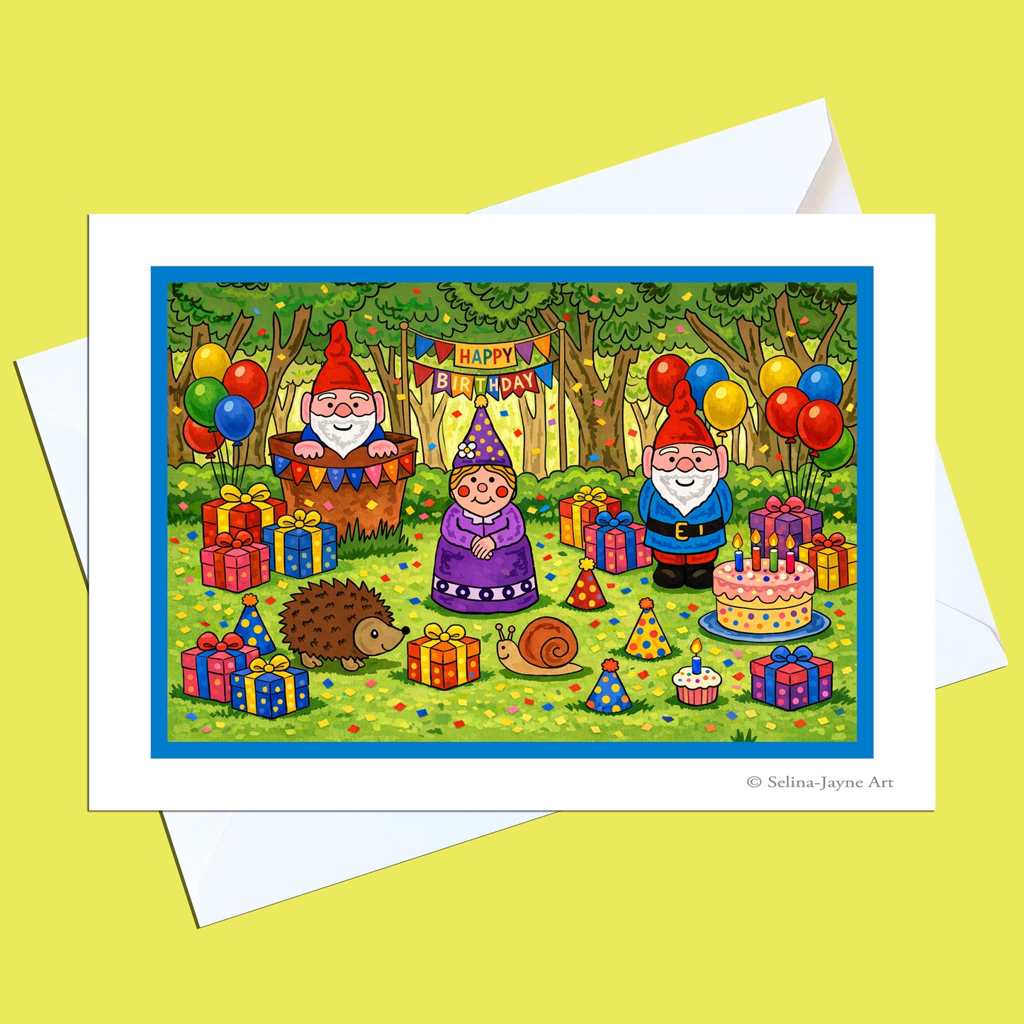 A square greeting card with a white border and white envelope, featuring a colorful cartoon birthday scene with gnome characters, balloons, presents, a hedgehog, a snail, and a birthday cake. The card is photographed on a pale yellow background.