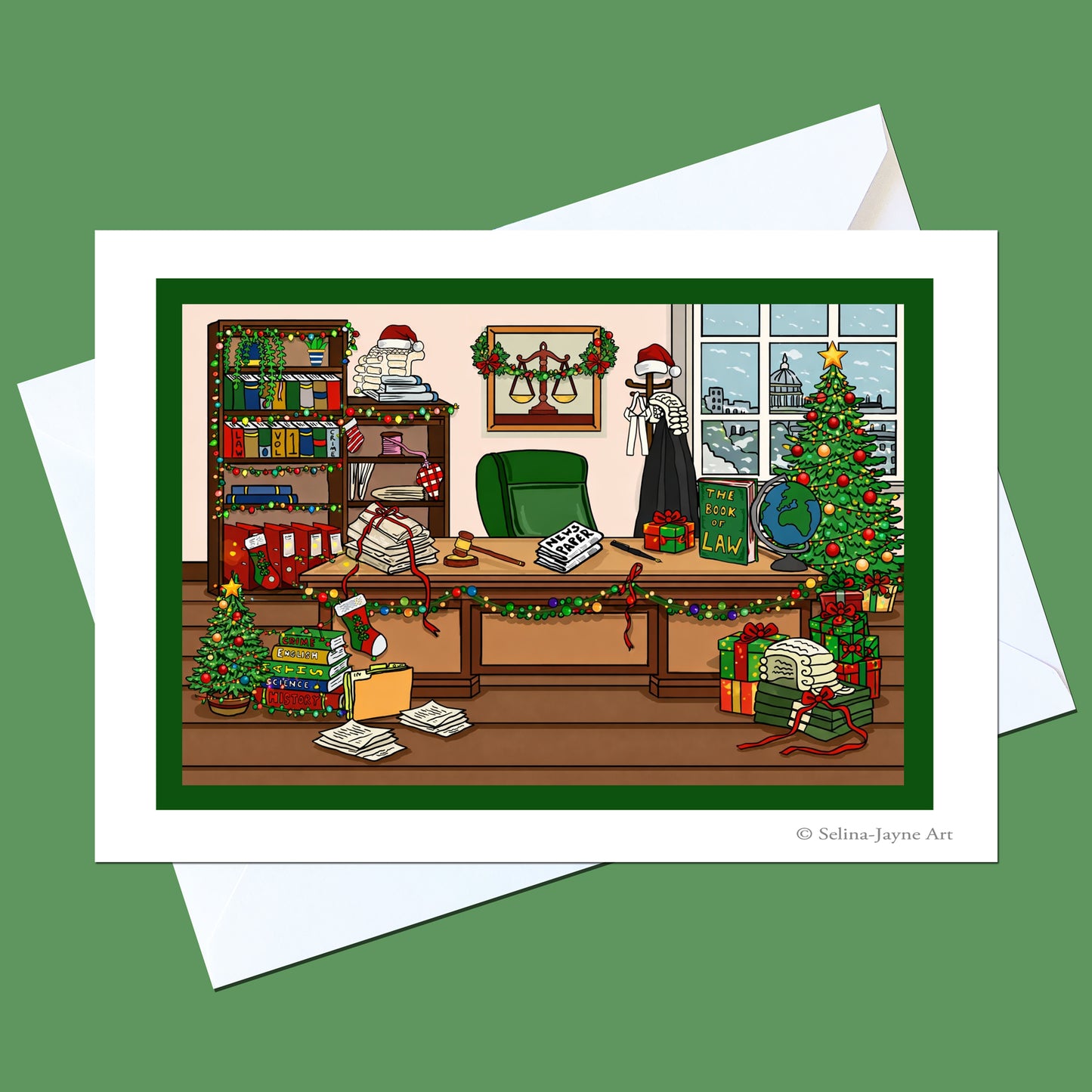 A holiday-themed art print card featuring a busy, decorated office scene with a Christmas tree, gifts, books, and a figure in a Santa hat, shown with white envelopes on a solid green background.