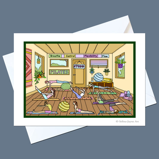A square art print or card featuring a colorful cartoon illustration of people practicing yoga in a studio, displayed on top of white envelopes against a slate blue background. The print includes the text 'Yoga' and 'Sattva' and is signed 'Selina Jayne Art' in the lower right.