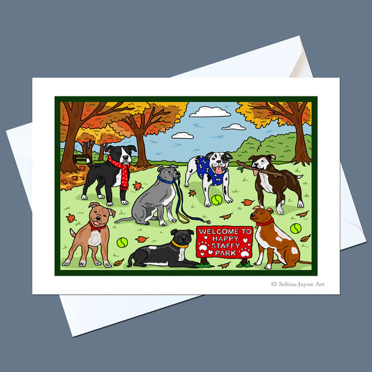 A square art print or greeting card featuring a colorful cartoon illustration of several dogs in an autumn park, shown with white envelopes on a slate blue background. The print has a white border and the artist's name 'Selina Jayne Art' is printed in the lower right corner.