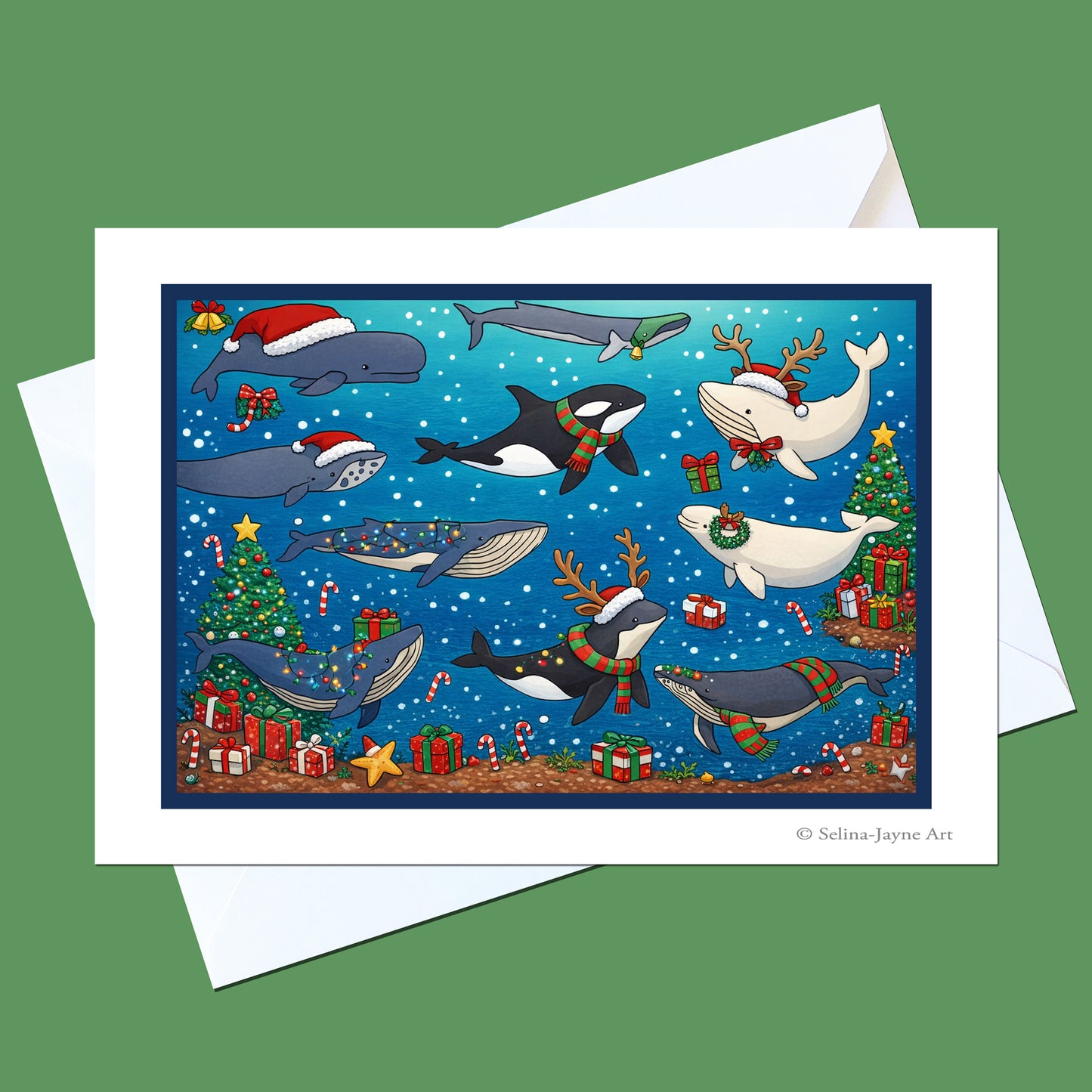 A Christmas-themed whale art print or greeting card shown with a white envelope on a solid green background. The card features a blue background with illustrated whales wearing holiday hats and scarves, Christmas trees, gifts, and snowflakes.