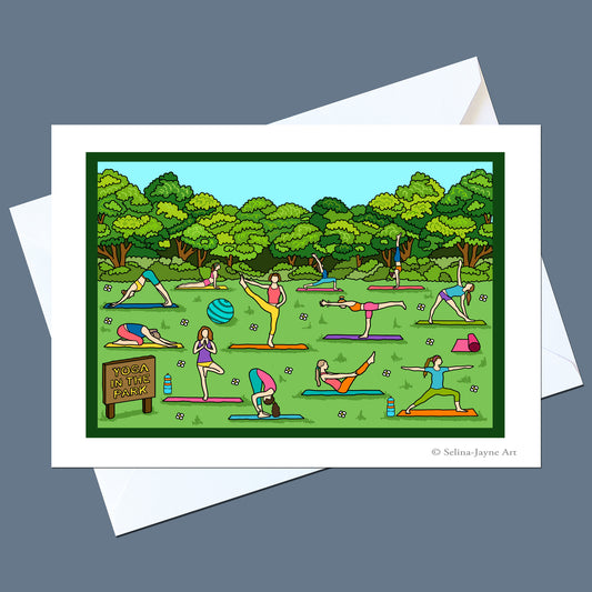 A square art print or greeting card featuring a colorful cartoon illustration of people practicing yoga in a park, shown with white envelopes on a dark gray background. The print includes the text 'YOGA VASALA PRANJA' and a small credit '© Selina Jaypee Art'.
